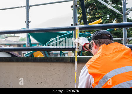 Muratore con un metro pieghevole e di alta visibilità giubbotti catarifrangenti Foto Stock