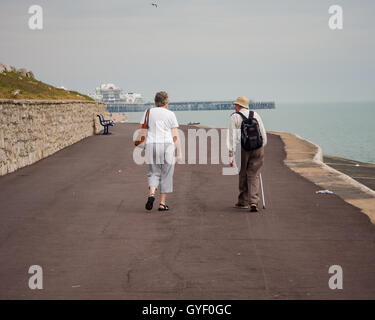 Una coppia senior a piedi lungo un deserto Southsea seafront Foto Stock