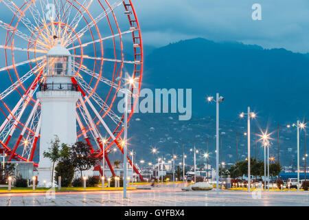 Batumi, Adjara, Georgia. Vista ravvicinata della ruota panoramica Ferris esattamente dietro il vecchio faro Bianco presso il lungomare di miracolo Park, amu Foto Stock