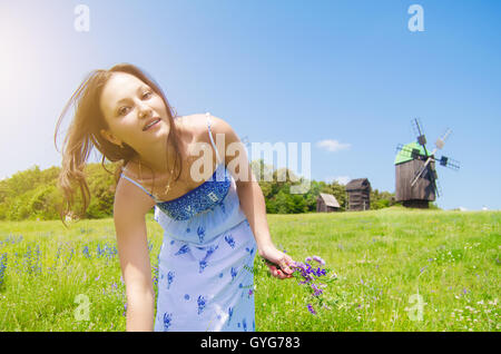 Ragazza camminare sul campo con un mazzo di fiori Foto Stock