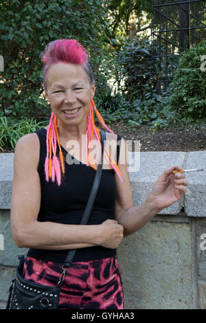 Una giovane donna nei suoi primi anni sessanta con colorate le estensioni di capelli. In Union Square Park a New York City. Foto Stock