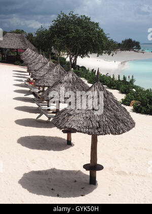 Vista guardando verso il basso su una riga con il tetto di paglia della pantina parasole ombrelli gettando ombre su una spiaggia di sabbia bianca Foto Stock