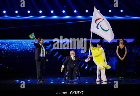 Il sindaco di Rio de Janeiro Eduardo Paes (sinistra) applaude come presidente della IPC Sir Philip Craven (centro) mani la Bandiera Paralimpica al Governatore di Tokyo Yuriko Koike durante l'undicesimo giorno del 2016 Rio Giochi Paralimpici di Rio de Janeiro in Brasile. Foto Stock