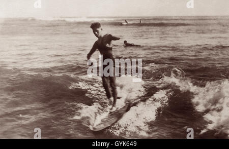 Surfer di equitazione con la tavola da surf in legno di Waikiki, Honolulu, Hawaii c1920s. Foto Stock