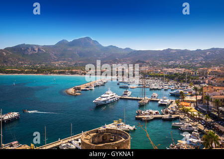 Vista della spiaggia di Calvi, case storiche in Calvi città vecchia con il turchese chiaro di acqua oceanica in porto con barche e yacht, Corsica Foto Stock