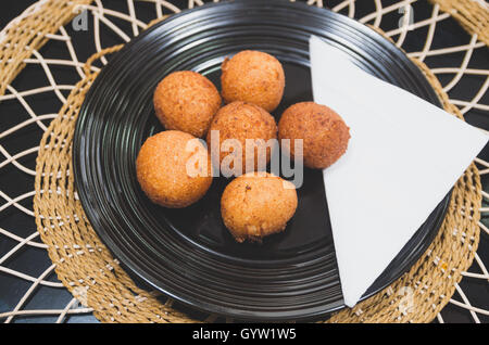 Fritte palline fatte da banane verdi seduto su piastra nera, tradizionale cibo latino-americano, elegante Impostazione tabella Foto Stock