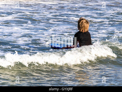 Ragazza giovane in muta braves le onde il boogie board Foto Stock