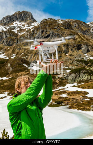 Giovane uomo le catture un drone in montagna, Rohrmoos-Untertal, Schladminger Tauern, Schladming, Stiria, Austria Foto Stock