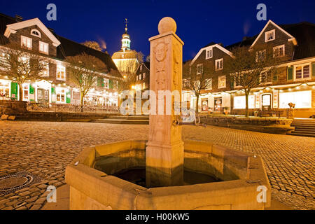 Storica fontana sul luogo di mercato e monastero chiesa nella città vecchia di Graefrath di sera, in Germania, in Renania settentrionale-Vestfalia, Bergisches Land, Solingen Foto Stock