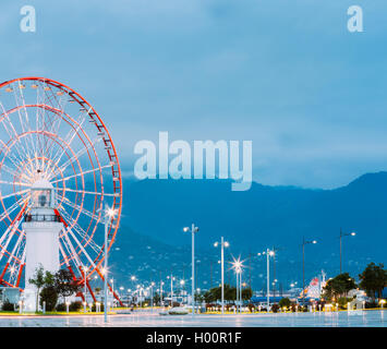 Batumi, Adjara, Georgia. Vista ravvicinata della ruota panoramica Ferris esattamente dietro il vecchio faro Bianco presso il lungomare di miracolo Park, amu Foto Stock