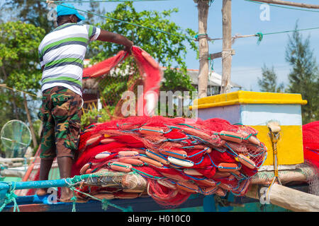 WELIGAMA, SRI LANKA - Marzo 7, 2014: pescatore preparazione rete da pesca su una barca. Il turismo e la pesca sono due attività principale in thi Foto Stock