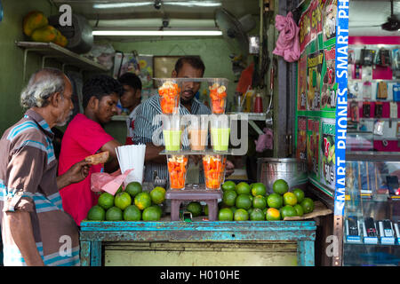COLOMBO, SRI LANKA - Febbraio 22, 2014: Locale uomo acquisto di succo di frutta da uno di molti fornitori di strada nella città. Foto Stock