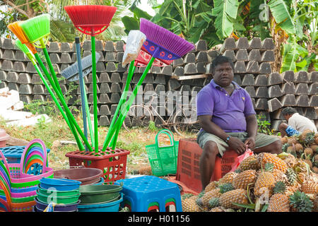 HIKKADUWA, SRI LANKA - Febbraio 23, 2014: Locale street venditore a vendere i prodotti in plastica e ananas. Il mercato della domenica grea Foto Stock