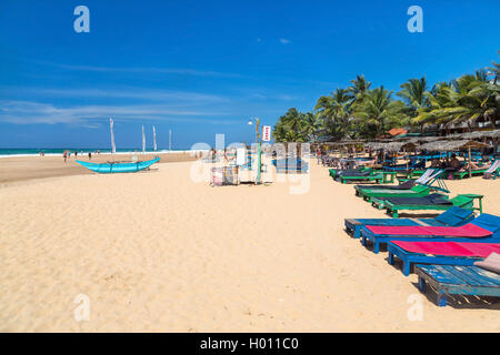 HIKKADUWA, SRI LANKA - 24 febbraio 2014: di legno sedie a sdraio sulla spiaggia sabbiosa. Hikkaduwa è ben noto turistico internazionale desti Foto Stock