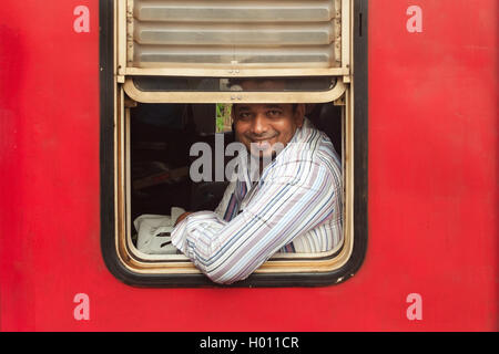 HIKKADUWA, SRI LANKA - Febbraio 22, 2014: Locale uomo in treno guardando attraverso la finestra. I treni sono molto economici e scarsamente mainta Foto Stock