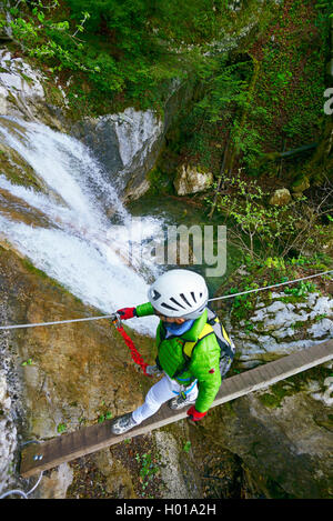 Scalatore sulla sospensione ponte in corrispondenza di una cascata, Via Ferrata Saint Vincent de Mercuze, Francia, Montalieu Foto Stock