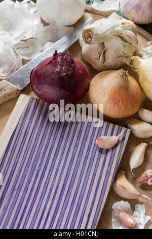 Organici di aglio e cipolla con un vecchio libro il coperchio e il coltello come una naturale ancora in vita per una sana e cibi vegetariani e cucina Foto Stock