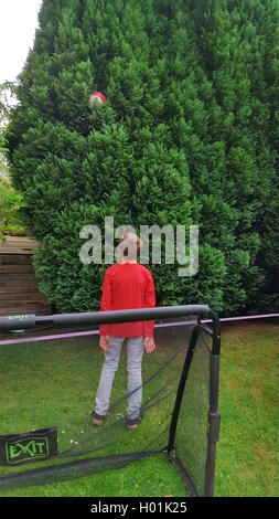 Ragazzo che guarda dopo un calcio in una struttura ad albero Foto Stock