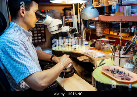 Gioielliere lavorando su metalli con dispositivo ottico che consente per lavori di precisione Foto Stock