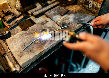 Gioielliere lavorazione barra di metallo mediante riscaldamento fino Foto Stock