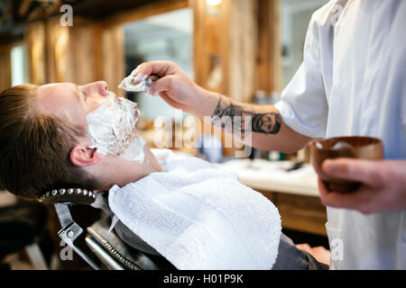 Retrò la rasatura con schiuma in un barbiere Foto Stock