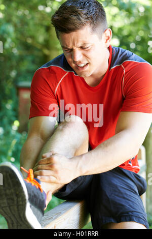 Uomo con sport pregiudizio subito pur esercitando all'aperto Foto Stock