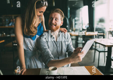 Donna e uomo flirtare in cafe mentre discutendo il contenuto della compressa Foto Stock