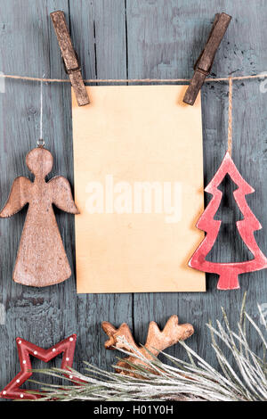 Decorazioni a forma di albero di Natale e di angelo e di vuoto della scheda Messaggi di saluto appeso su una stringa su sfondo vecchio Foto Stock