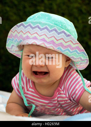 Bambino con cappello per il sole sdraiati su un prato e pianto, Austria Foto Stock
