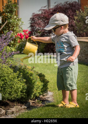 Ragazzino con irrigazione irrigazione può fiori in estate, Austria Foto Stock