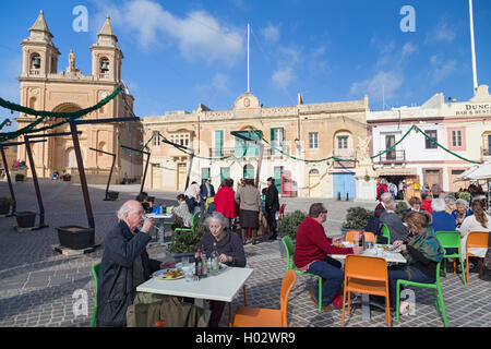 MARSAXLOKK, Malta - 11 gennaio 2015: persone mangiare presso il ristorante terrazza di fronte alla chiesa parrocchiale di Nostra Signora di Pompei. Foto Stock