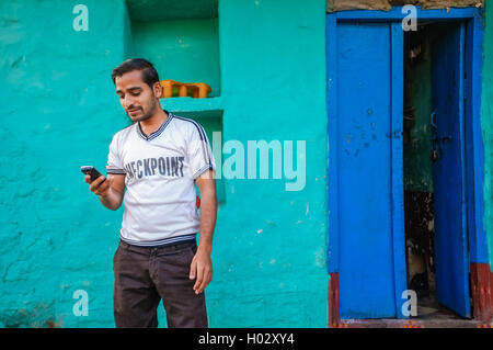 KAMALAPURAM, India - 02 febbraio 2015: Indiano uomo guardando a questo telefono cellulare al di fuori della sua casa Foto Stock