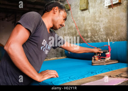 MUMBAI, India - 08 gennaio 2015: uomo stiratura con un ferro da stiro elettrico in ambienti interni in Dhobi ghat. Foto Stock