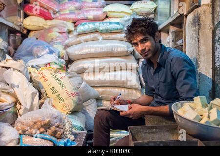 JODHPUR, India - 10 febbraio 2015: Giovani India uomo si siede in negozio e scrive i giorni verso il basso reddito nel notebook. In ritardo le ore di lavoro sono Foto Stock