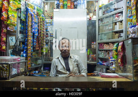 JODHPUR, India - 11 febbraio 2015: fornitore indiano si siede in negozio con gutka appesi in background e altri prodotti. Gutka ha mil Foto Stock