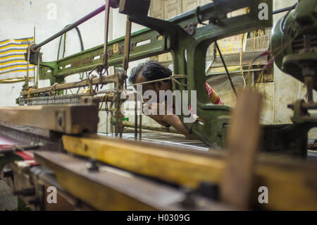 VARANASI, India - 21 febbraio 2015: lavoratore le riparazioni della macchina tessile in fabbrica piccola. Foto Stock