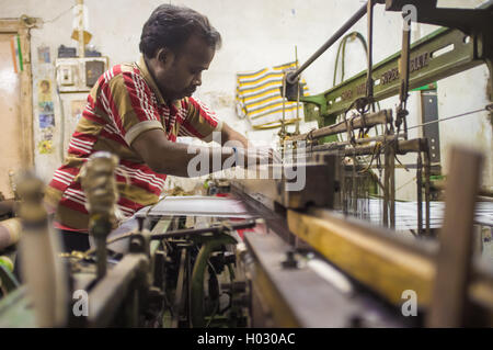 VARANASI, India - 21 febbraio 2015: lavoratore le riparazioni della macchina tessile in fabbrica piccola. Foto Stock