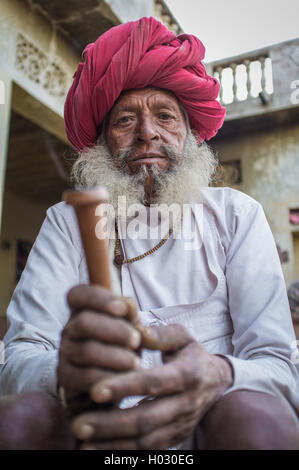 Regione GODWAR, India - 12 febbraio 2015: Anziani Rabari tribesman con il tradizionale turbante, vestiti e lunga barba detiene chillum. Foto Stock