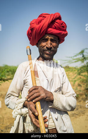 Regione GODWAR, India - 13 febbraio 2015: Rabari tribesman contiene ax tradizionale sul campo. Rabari o Rewari sono un Indiano communi Foto Stock