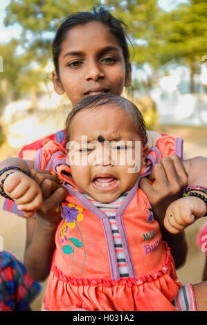HAMPI, India - 31 gennaio 2015: il bambino indiano con bindi piangendo mentre viene trattenuto dal membro della famiglia Foto Stock
