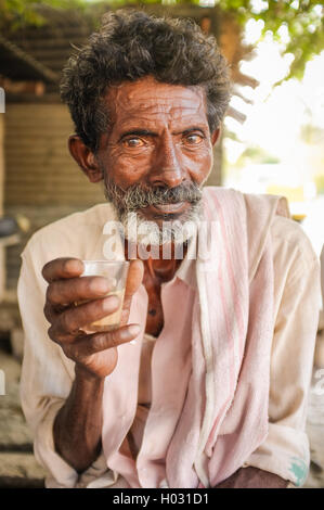 HAMPI, India - 31 gennaio 2015: Anziani uomo indiano tenendo un bicchiere di chai Foto Stock