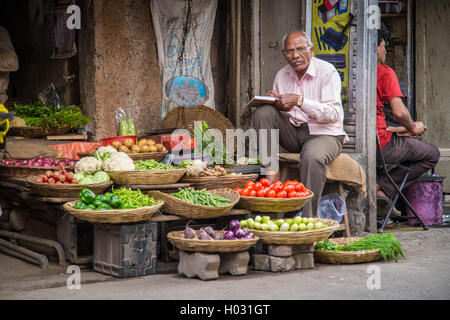 MUMBAI, India - 17 gennaio 2015: Anziani commerciante indiano attende i clienti nella parte anteriore del negozio di alimentari in Market street. Foto Stock