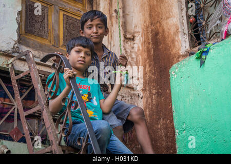 MUMBAI, India - 12 gennaio 2015: due giovani ragazzi siedono su alti gradini nella parte anteriore della casa in Dharavi slum. Dharavi è uno dei grandi Foto Stock