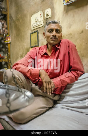 JODHPUR, India - 07 febbraio 2015: Proprietario del negozio seduti rilassati all'interno del magazzino in attesa per i clienti. Oltre a buon mercato labore Foto Stock