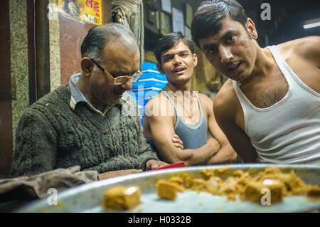 JODHPUR, India - 07 febbraio 2015: Candy il proprietario del negozio accanto a due lavoratori di finitura giorno completo innesto. I lavoratori di tutto l'India sono la maggior parte del Foto Stock