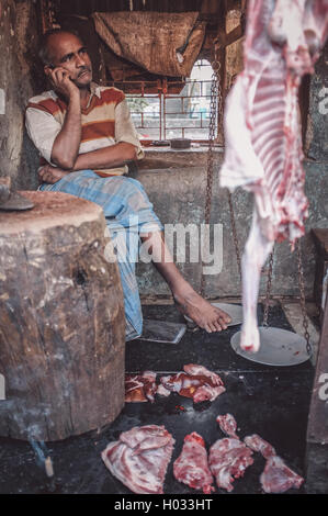 MUMBAI, India - 12 gennaio 2015: Indiano macellaio parla sul cellulare al lavoro in Dharavi slum. Post-elaborati con grano, tessitura Foto Stock