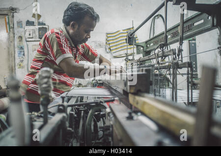 VARANASI, India - 21 febbraio 2015: lavoratore le riparazioni della macchina tessile in fabbrica piccola. Post-elaborati con grano, texture e colo Foto Stock