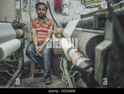 VARANASI, India - 21 febbraio 2015: lavoratore siede sulla sedia accanto alla macchina tessile in fabbrica piccola. Post-elaborati con grano, te Foto Stock