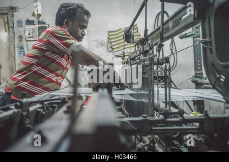 VARANASI, India - 21 febbraio 2015: lavoratore le riparazioni della macchina tessile in fabbrica piccola. Post-elaborati con grano, texture e colo Foto Stock