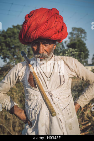 Regione GODWAR, India - 14 febbraio 2015: Anziani Rabari tribesman con turbante rosso e il tradizionale ax sulle spalle. Post-proces Foto Stock